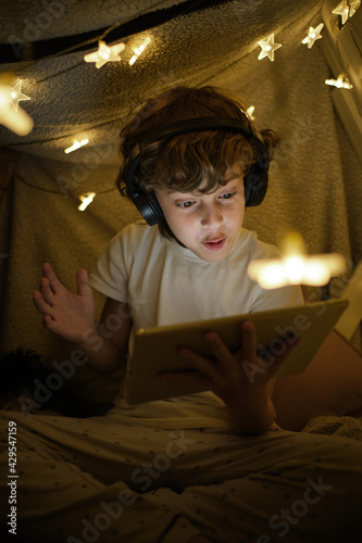 Canvas Print Excited boy watching video on tablet in blanket fort