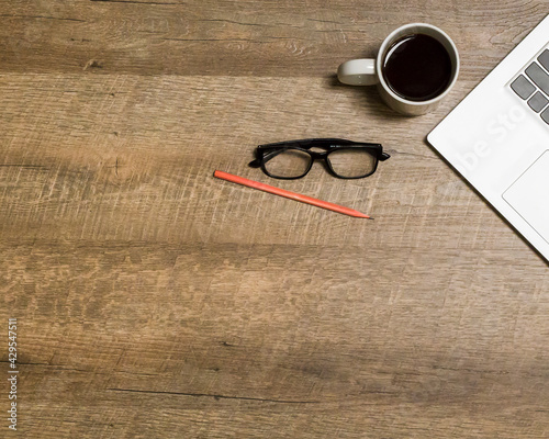 Notebook, coffee cup, glasses, pencil, on a wooden background.