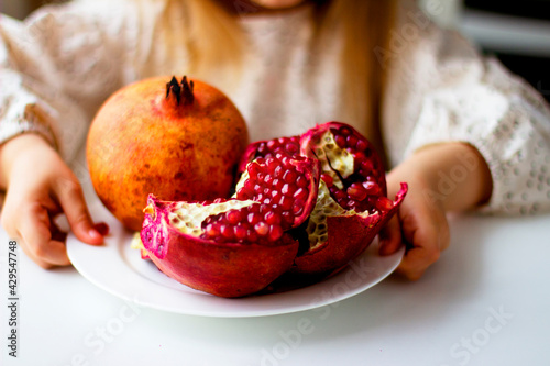 Little girl holding a pomegranate. Symbol of the Jewish New Year. Rosh ha Shana. Healthy organic sweet fruits. 