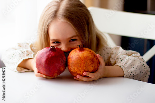 Little girl holding a pomegranate. Symbol of the Jewish New Year. Rosh ha Shana. Healthy organic sweet fruits. 