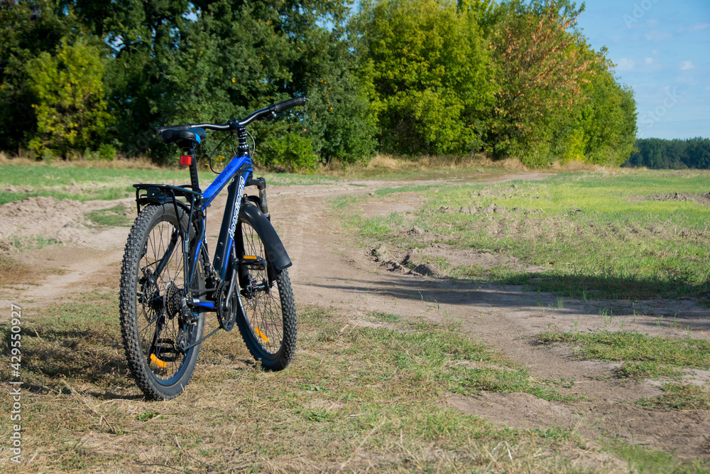 Mountain bike. bike stands on in the field. A mountain bike stands on a field path with green grass. cycling. outdoor cycling activities. space for text. editorial, Ukraine, Kiev region 2020 Mountain bike. bike stands on in the field. A mountain bike stands on a field path with green grass. cycling. outdoor cycling activities. space for text. editorial, Ukraine, Kiev region 2020