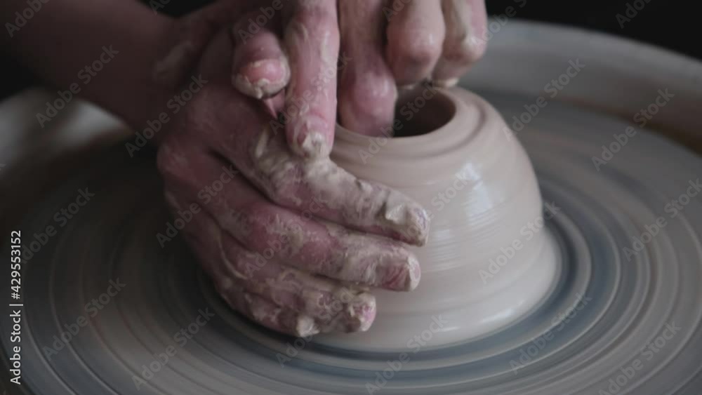 In this video, we watch a woman working on a potter's wheel, creating a pitcher of clay with her own hands in a workshop. No face, close-up, 4K, 25 fps. In this video, we watch a woman working on a potter's wheel, creating a pitcher of clay with her own hands in a workshop. No face, close-up, 4K, 25 fps.