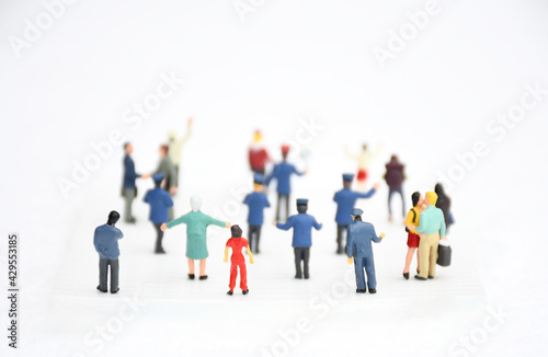 Top view group of miniature people in different colors costume, generation and career stand on white background. Concept communication of society and social distancing. selective focus.