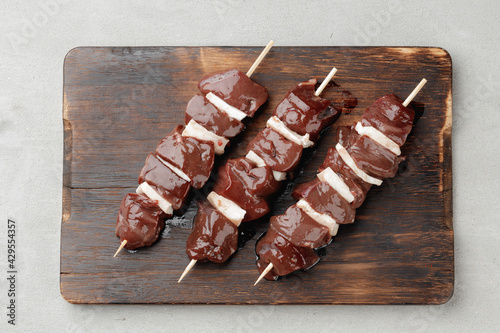 Raw beef liver on skewers on board