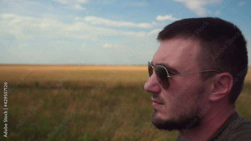 Portrait of a Young Man in Sunglasses on the Background of a Wheat Field and Blue Sky. Portrait of a Young Man in Sunglasses on the Background of a Wheat Field and Blue Sky.