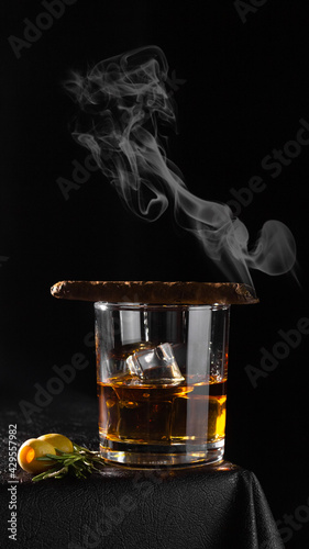 Cognac, rum, whiskey or other alcoholic beverage in a glass glass on a black background. Cigar on a glass.