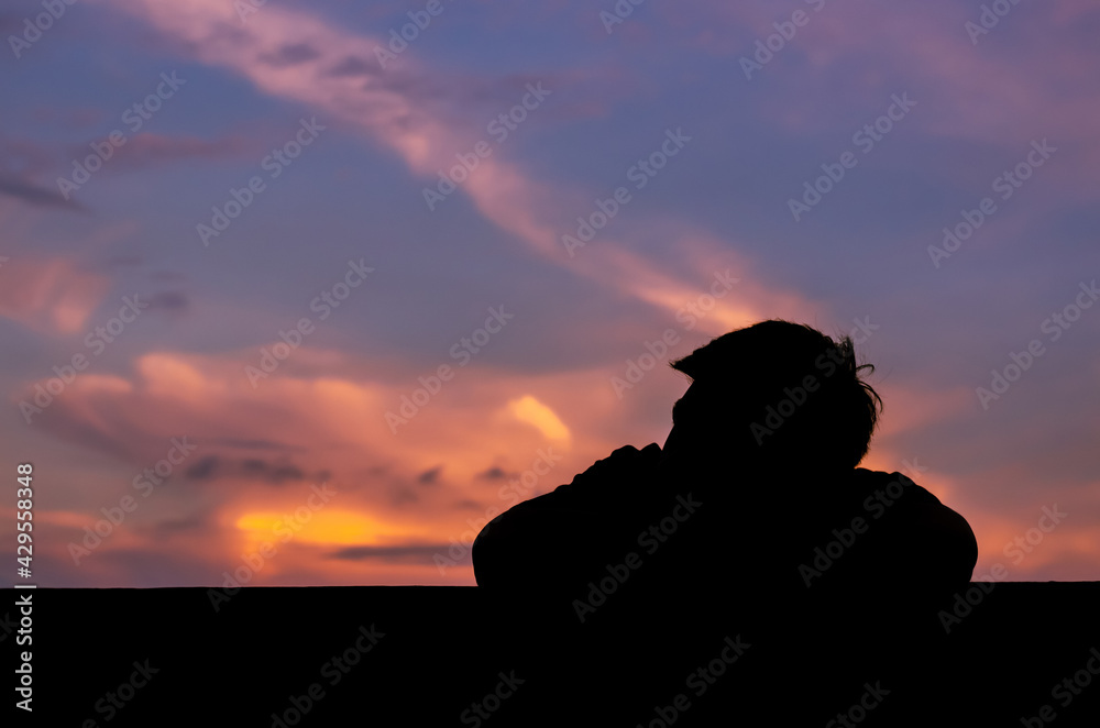 Silhouette of asian man stay alone with dusk sky background. Depression and mental health concept.