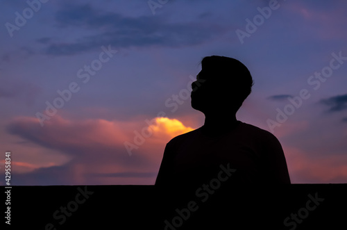 Silhouette of asian man stay alone with dusk sky background. Depression and mental health concept.