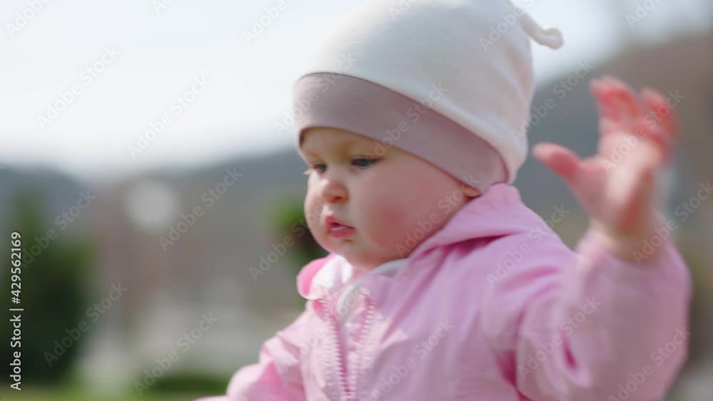 A cute baby smiles and walks unsteadily around his mother. A mother kisses and hugs her child. Close-up portrait. View from the bottom corner. Recreation in the park. A cute baby smiles and walks unsteadily around his mother. A mother kisses and hugs her child. Close-up portrait. View from the bottom corner. Recreation in the park.