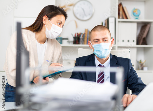 Business coworkers man and woman in protective fase masks discussing new ideas and brainstorming in modern office