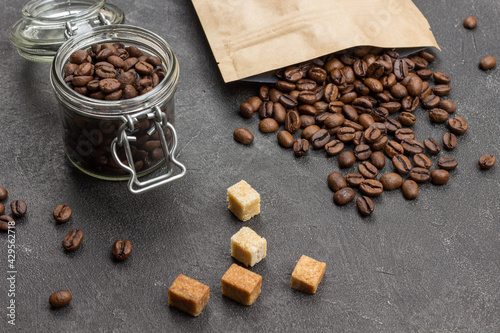 Roasted coffee beans in glass jar and in paper bag.