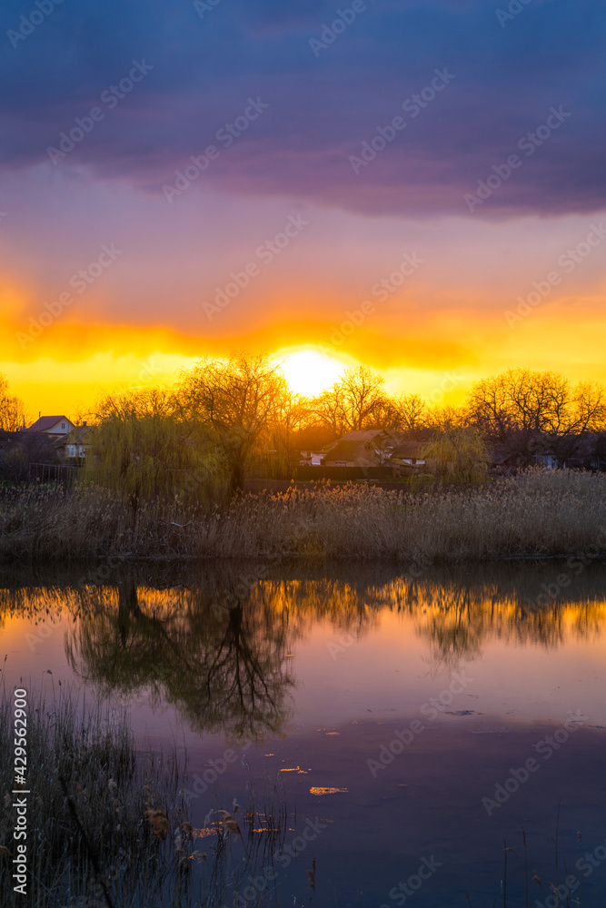 Beautiful golden sunset with reflection of clouds in the lake in the village panorama Beautiful golden sunset with reflection of clouds in the lake in the village panorama