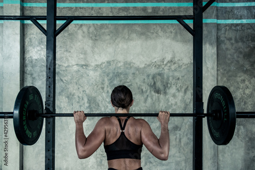 Canvas Print A beautiful female athlete prepares to do a barbell back squat at a gym