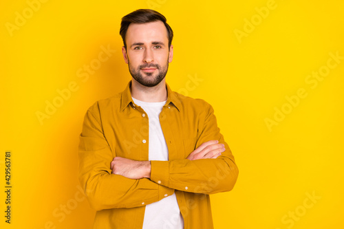Photo of handsome serious young guy wear casual clothes arms crossed empty space isolated yellow color background