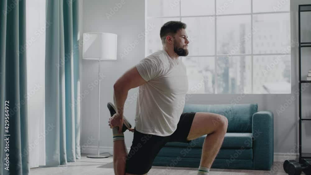 Skilled bodybuilder in t-shirt and shorts stretches legs Skilled bodybuilder in t-shirt and shorts stretches legs