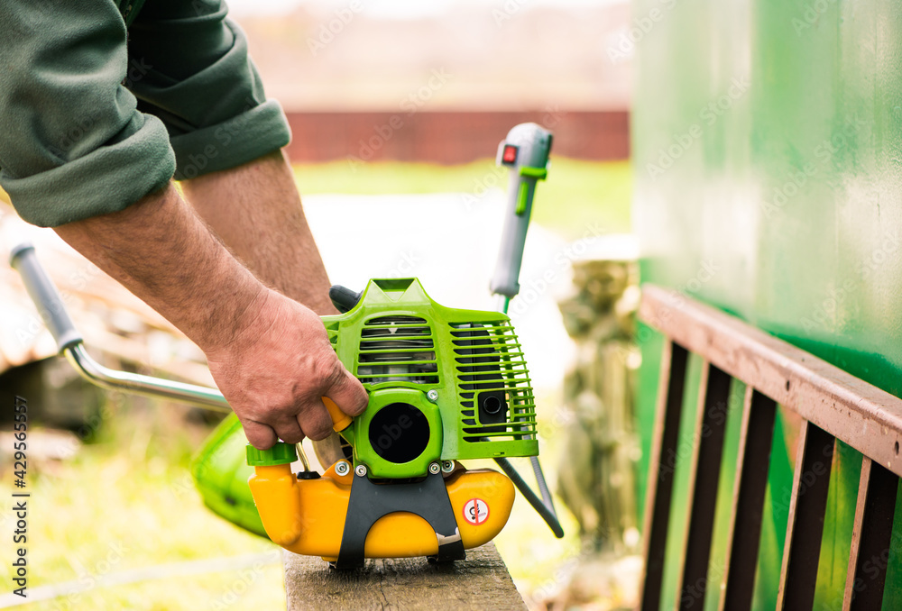 farmer prepares grass mower for work on farmland soil in spring farmer prepares grass mower for work on farmland soil in spring