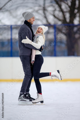 Youth Lifestyle. Positive Caucasian Couple Skating Together While Standing Embraced On Skatingrink And Having Good Time Outdoors.