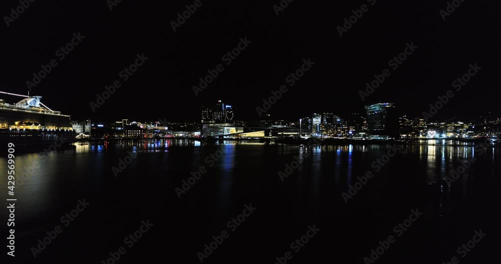 Drone flight above Oslo fjord towards golden illuminated Opera house at night Drone flight above Oslo fjord towards golden illuminated Opera house at night