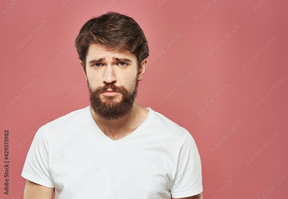Fototapeta premium A man in a white T-shirt with a beard on a pink background Copy Space