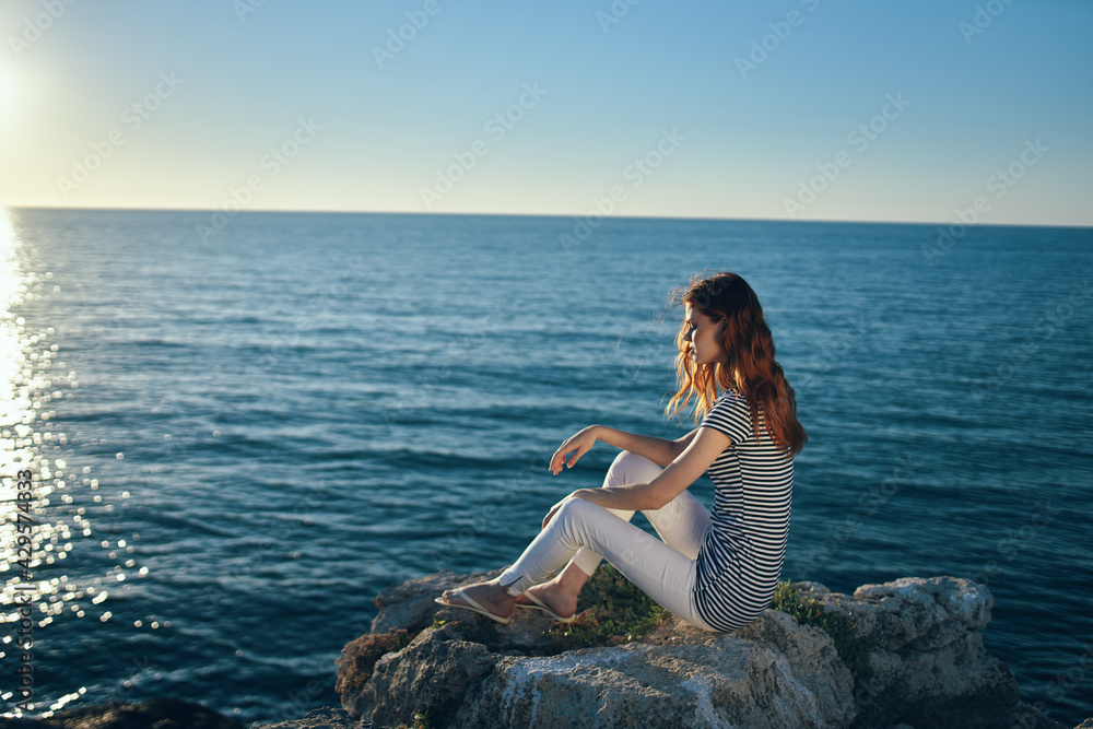 the traveler sits on the beach near the sea in the mountains and sunset