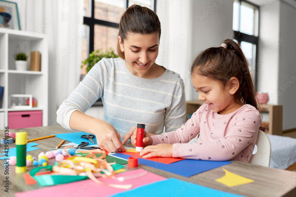 family, art and craft concept - mother spending time with her little daughter with glue making applique of color paper at home family, art and craft concept - mother spending time with her little daughter with glue making applique of color paper at home