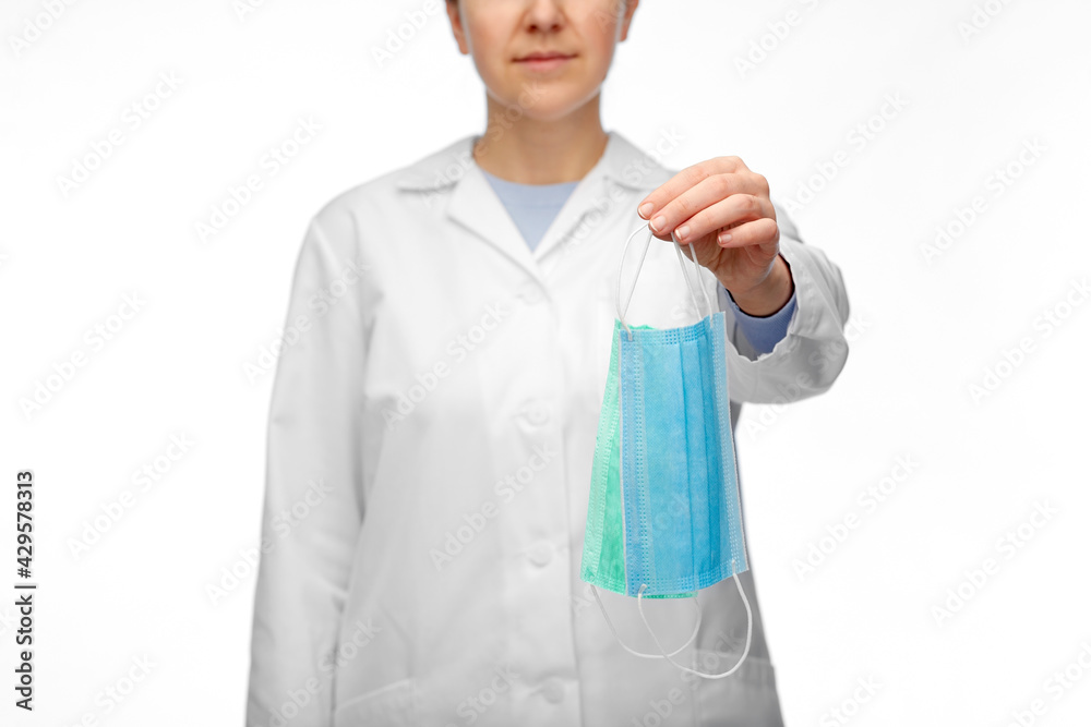 medicine, health protection and healthcare concept - close up of female doctor in white coat showing two medical masks over white medicine, health protection and healthcare concept - close up of female doctor in white coat showing two medical masks over white
