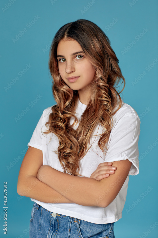 portrait of cute curly teen girl on blue background. portrait of cute curly teen girl on blue background.