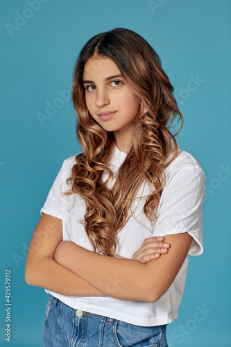 portrait of cute curly teen girl on blue background.