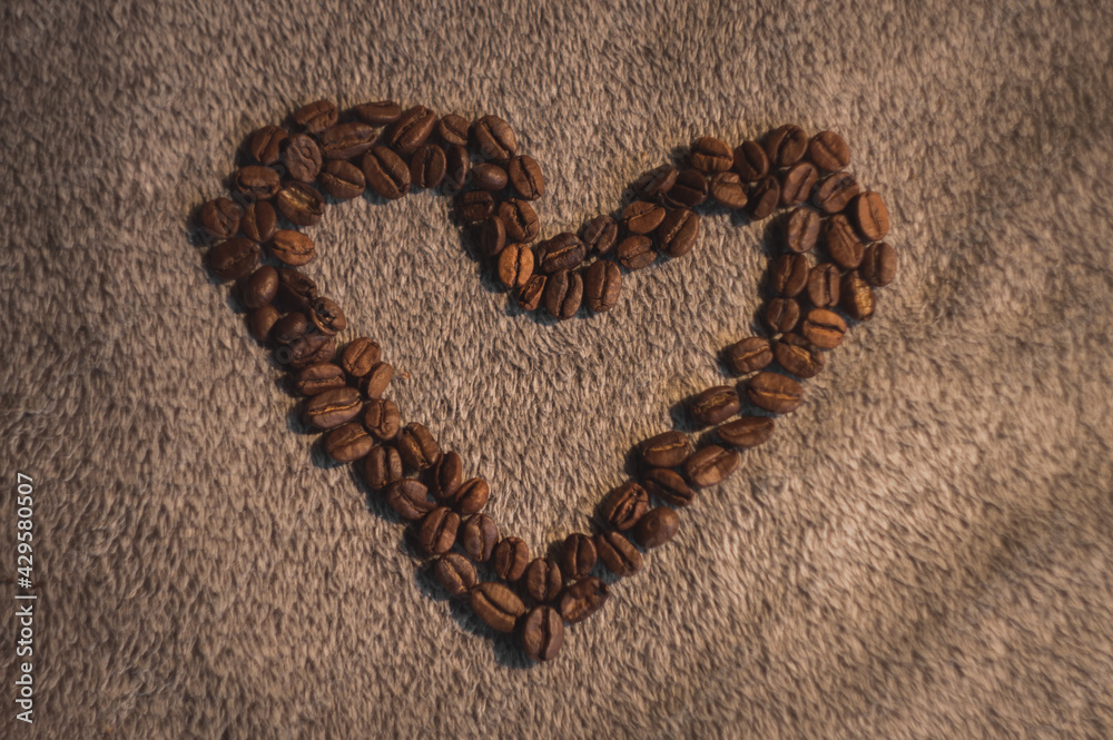Heart arranged from delicious black coffee on a soft blanket background Heart arranged from delicious black coffee on a soft blanket background