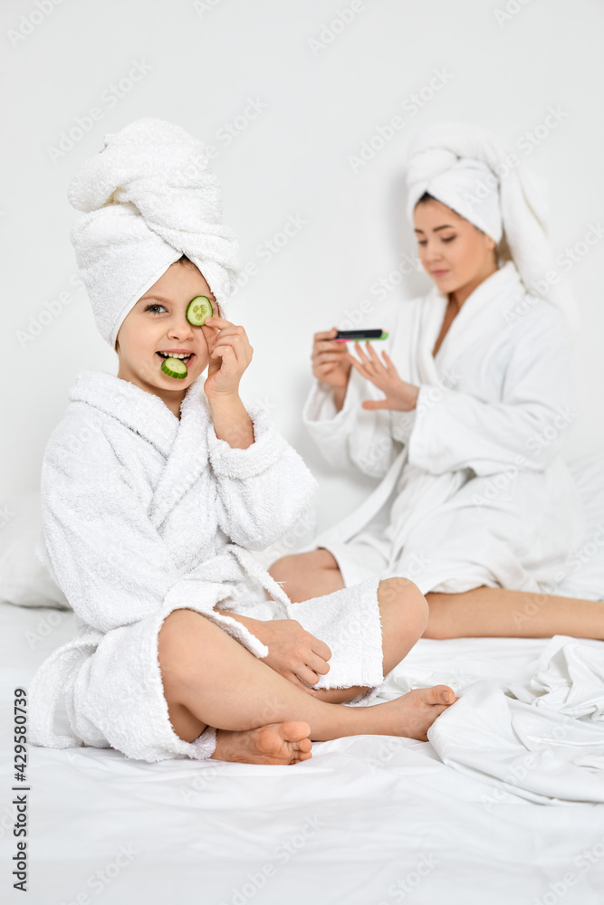 little daughter holding cucumber slices and mom holding nail file little daughter holding cucumber slices and mom holding nail file