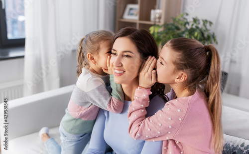 people, family and concept - happy mother and two daughters gossiping at home