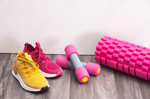 sports at home - sneakers of different colors, dumbbells and a massage roller