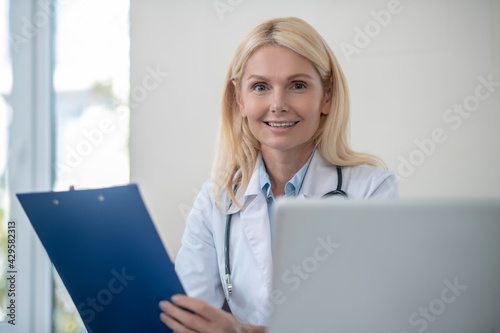 Happy woman doctor with folder in office