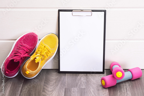 pink and yellow sneakers, dumbbells and a note board