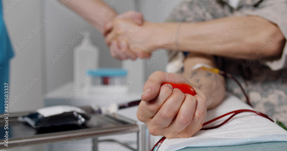 Close up of military officer donating blood and shaking hands with nurse