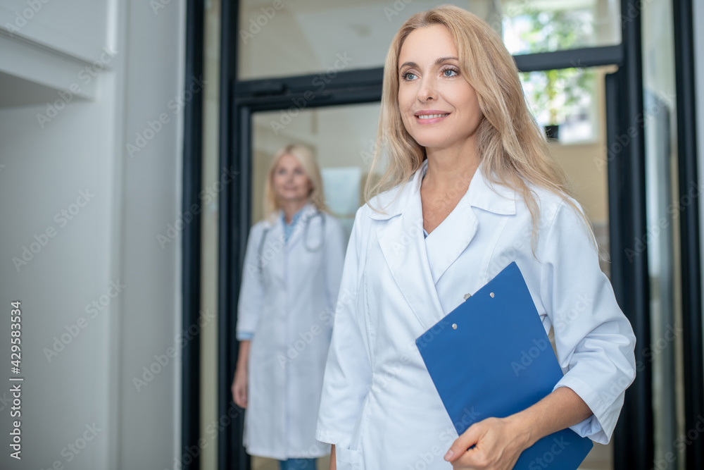 Successful female doctor walking down hallway and colleague Successful female doctor walking down hallway and colleague