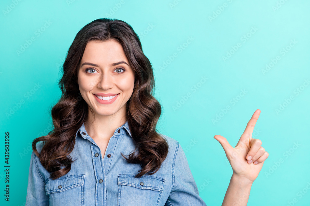 Photo of young cheerful girl happy positive smile point finger empty space ad advice choice isolated over turquoise color background Photo of young cheerful girl happy positive smile point finger empty space ad advice choice isolated over turquoise color background