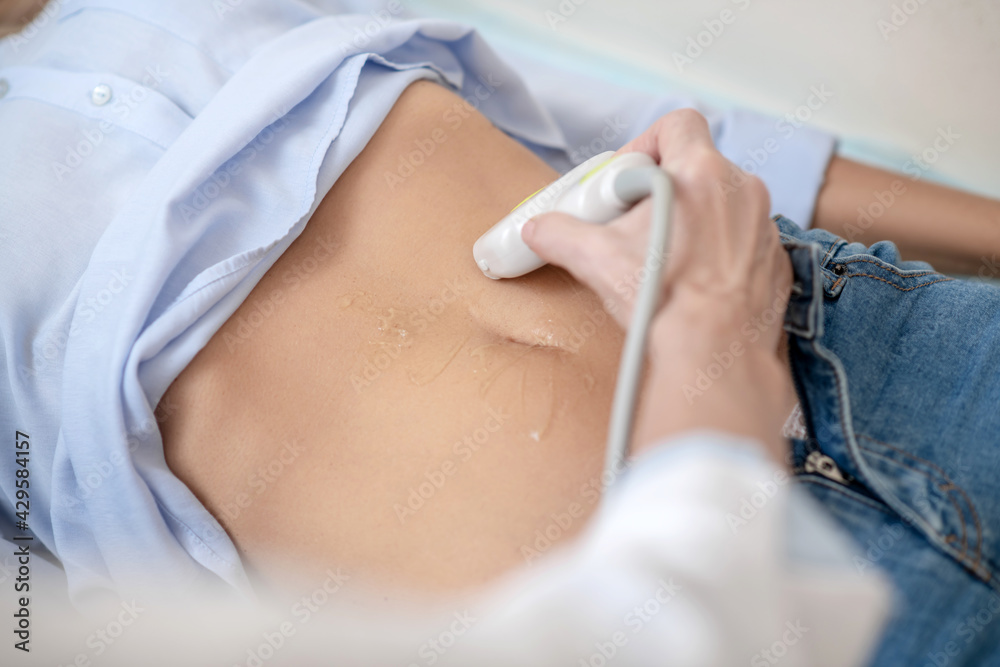 Fototapeta premium Ultrasound probe sliding on special gel on abdomen