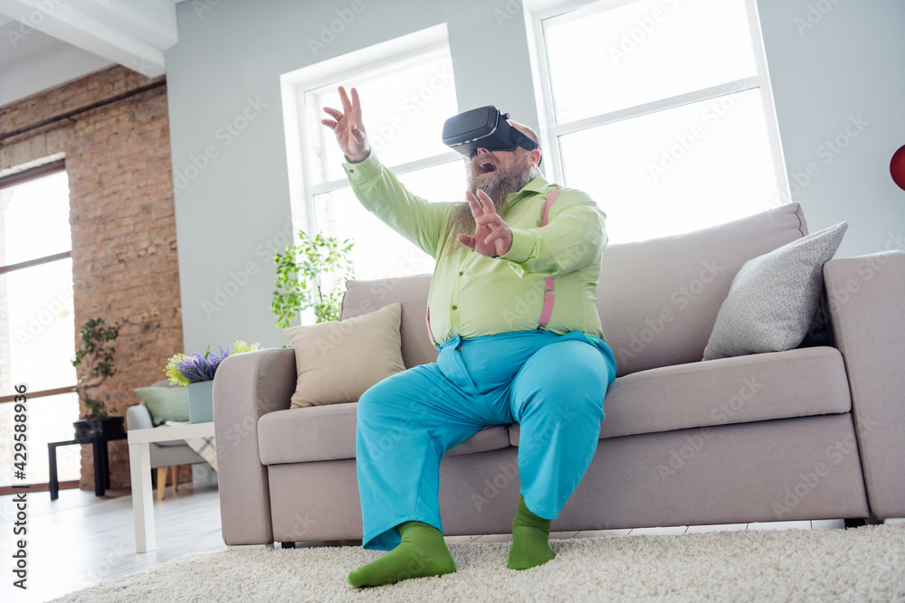 Photo of excited funny big abdomen guy dressed green shirt 3d glasses sitting couch rising hands arms indoors apartment room