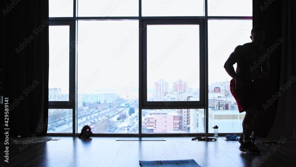 Sports training in studio with panoramic windows - a silhouette of shirtless muscular man jumping on the distance Sports training in studio with panoramic windows - a silhouette of shirtless muscular man jumping on the distance