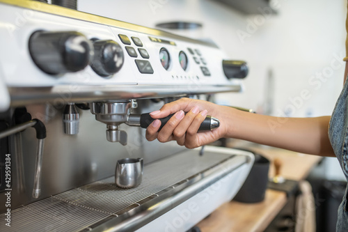 Womans hand holding holder of coffee machine