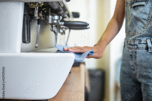 Womans hand with napkin sliding on coffeemaker