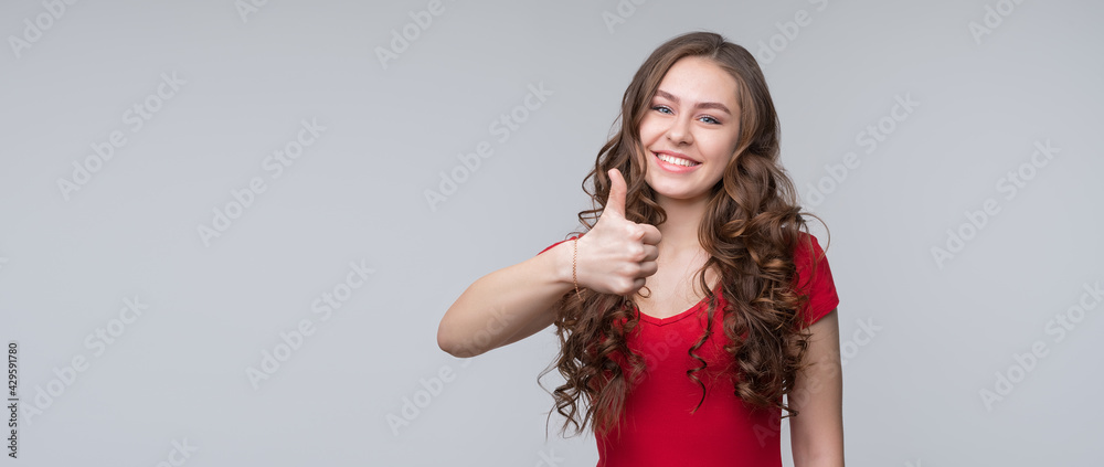 Beautiful young woman with long thick curly hair wearing red t shirt showing thumb up gesture and smiling Beautiful young woman with long thick curly hair wearing red t shirt showing thumb up gesture and smiling