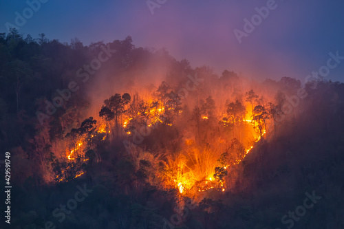 Wildfires on the mountain tops in the evening after sunset began to see more clearly the orange glow of the fire, the cause of the toxic dust floating in the air. Blue sky background