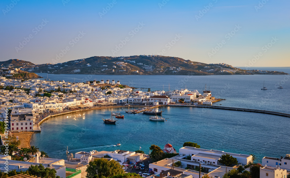 Beautiful sunset, colorful view, Mykonos, Greece. Bay, port, cruises, ship, whitewashed houses. Vacations, leisure, Mediterranean lifestyle