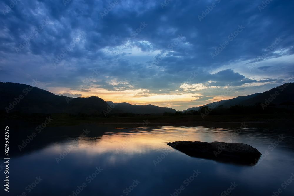  scenery silhouette Mountains The sky cools after the sun goes down, the rain clouds are moving, reflecting the water in the river, there are rocks in the water, giving a feeling of loneliness.