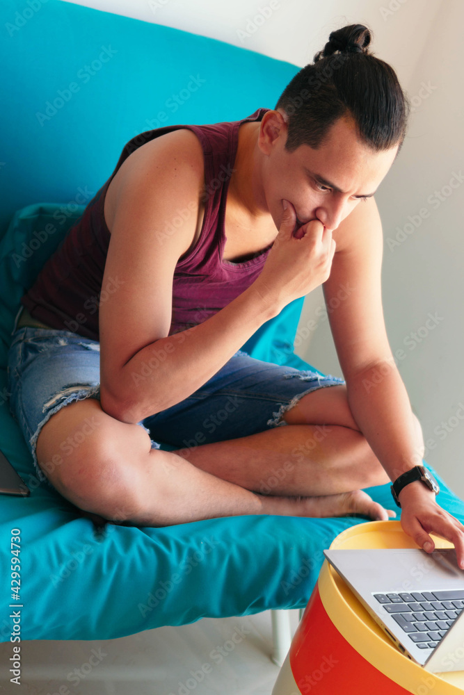 Obraz premium Man sitting on the sofa using a laptop