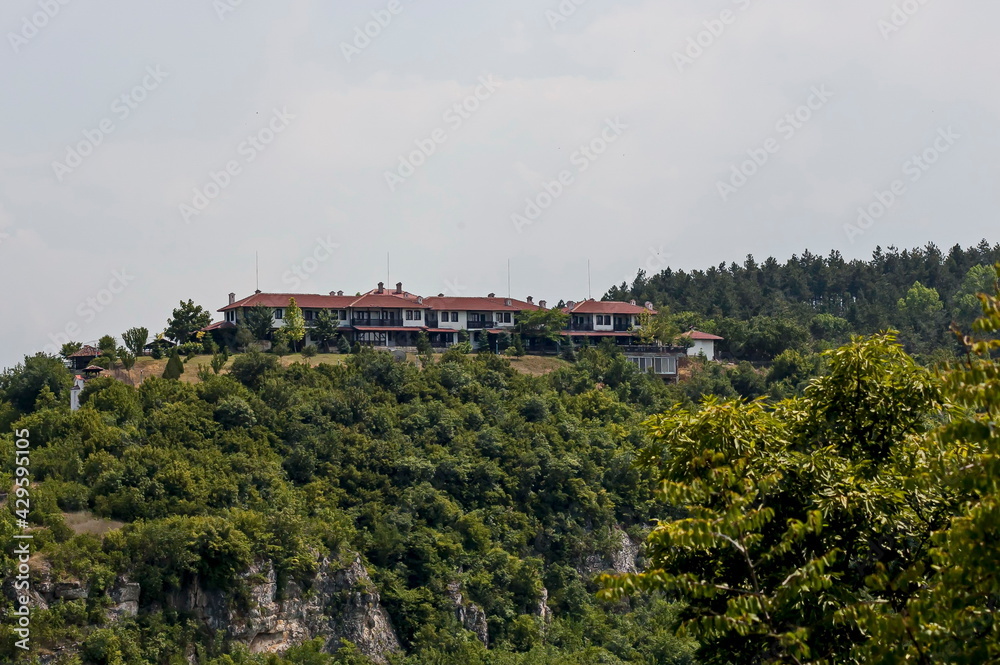 View of the beautiful village of Cherven village, Bulgaria, located below, above and in the high limestone cliffs, protected by magnificent deciduous trees 