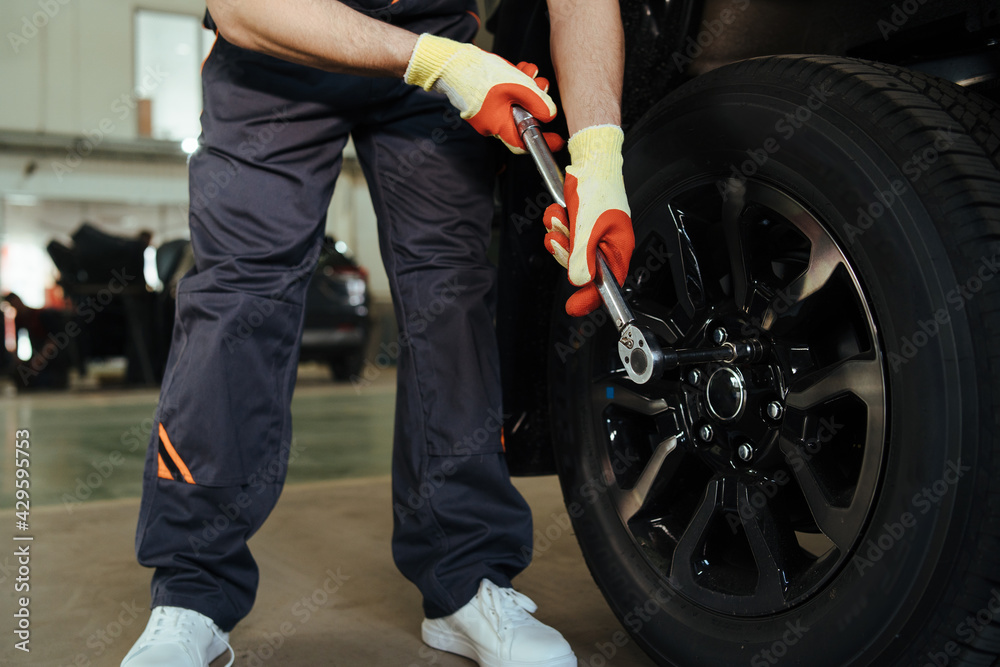 Mechanic changing a wheel and tire of modern car in workshop Mechanic changing a wheel and tire of modern car in workshop