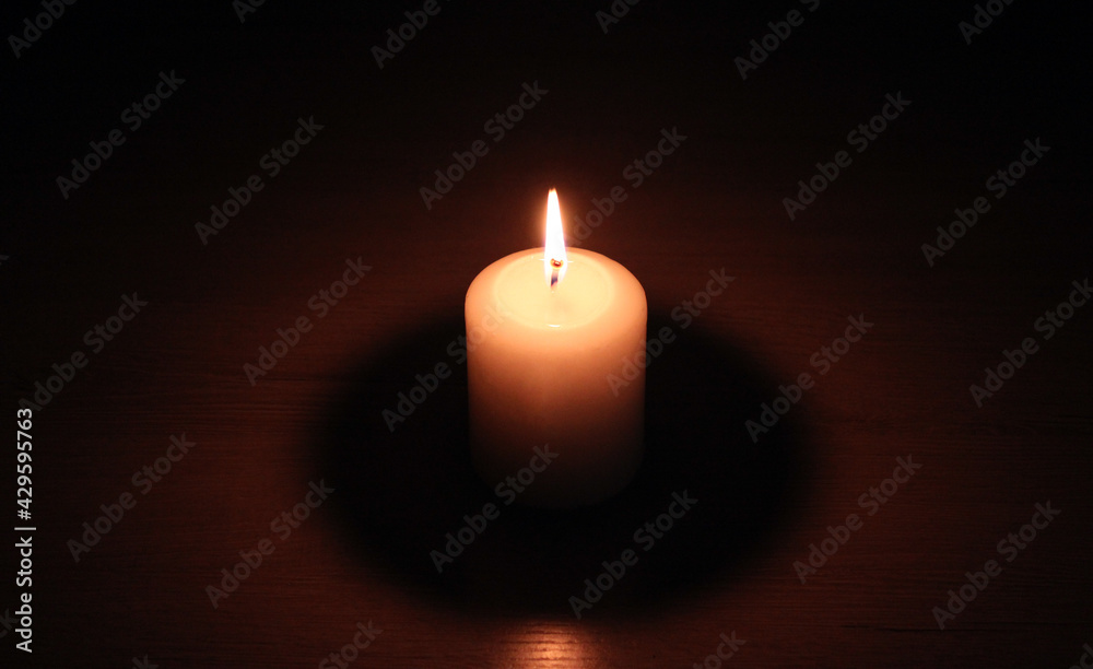 Burning candle on a wooden table in the dark Burning candle on a wooden table in the dark